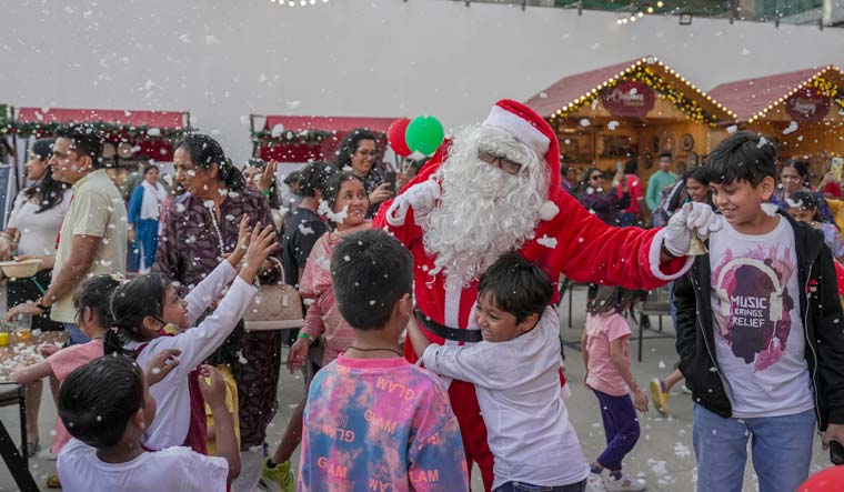 Children play with a man dressed as Santa Claus during a Christm